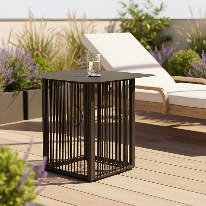 Schwarzer quadratischer Beistelltisch mit Wasserglas neben einer Gartenliege