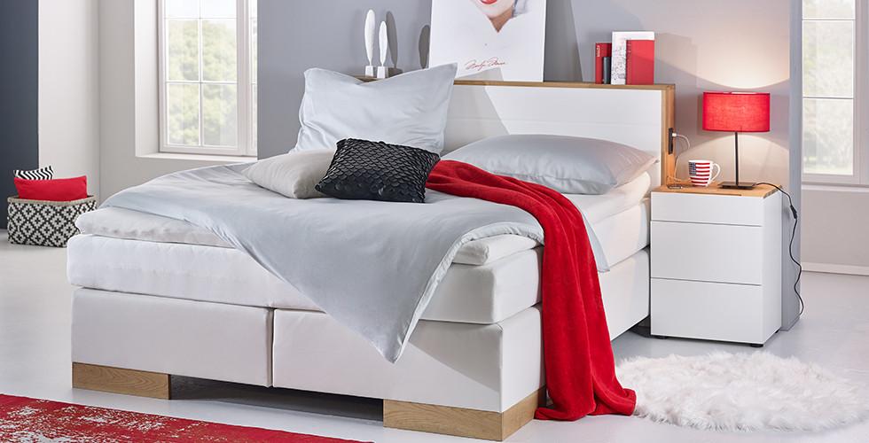 Edles, weißes Lederlook-Boxspringbett mit Eichenholzfüßen, inklusive Strom- und USB-Anschlüssen von mömax.