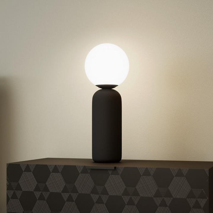 Schwarze Tischleuchte auf schwarzem Sideboard