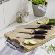 Schneidebrett mit einigen Messern und einer geschnittenen Gurke auf einer weißen Arbeitsplatte