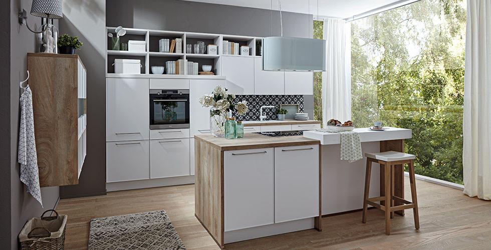 Wohnküche und Kücheninsel in Holznachbildung mit weißen Fronten und modernen Elektrogeräten von mömax.