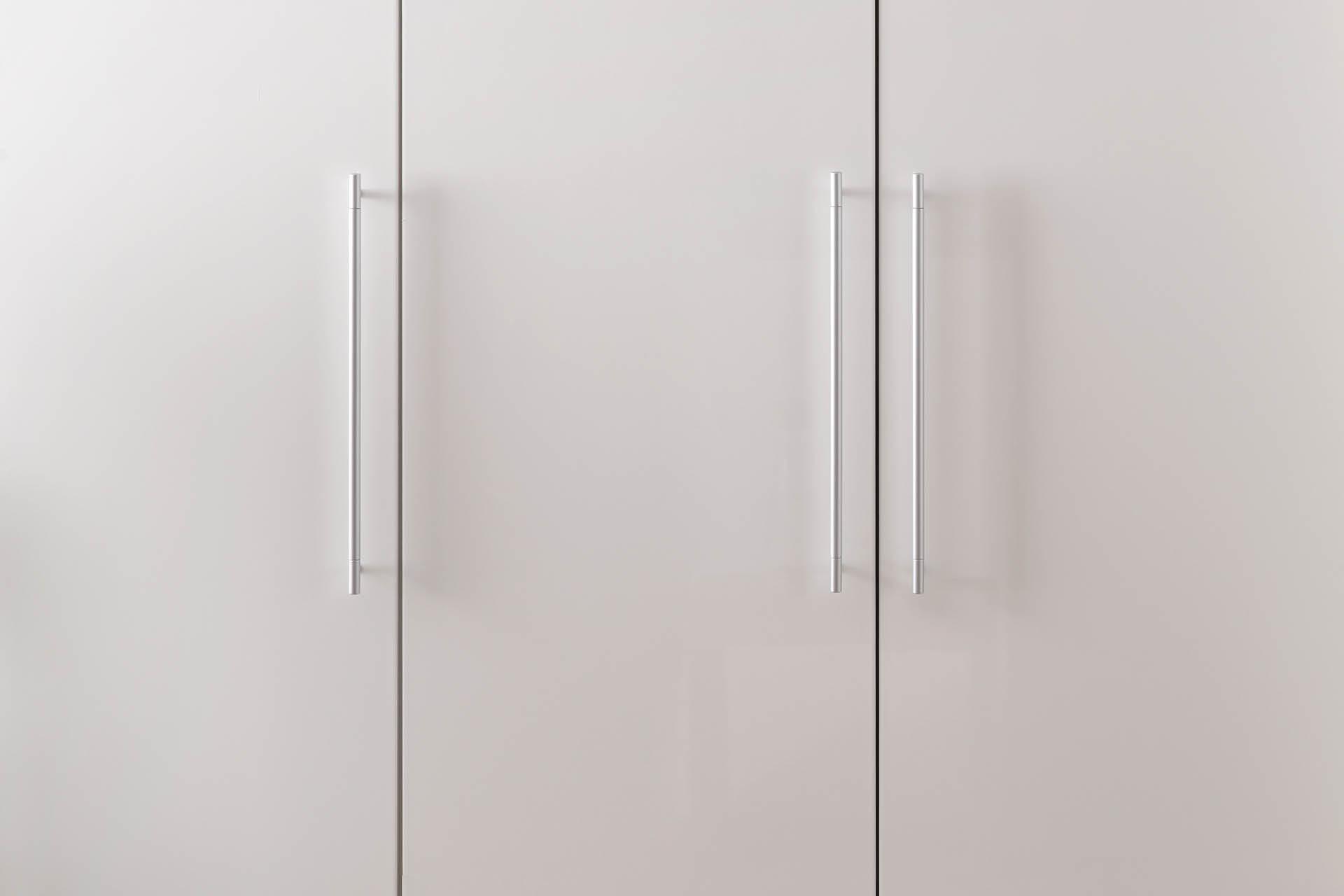 Kleiderschrank Detail silberfarbene Griffe auf weißen Fronten