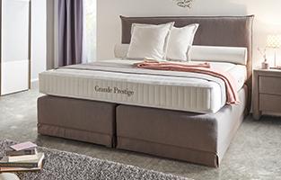 Graues Boxspringbett von mömax mit stabiler Federbox und Tonnentaschenfederkern-Matratze von mömax.