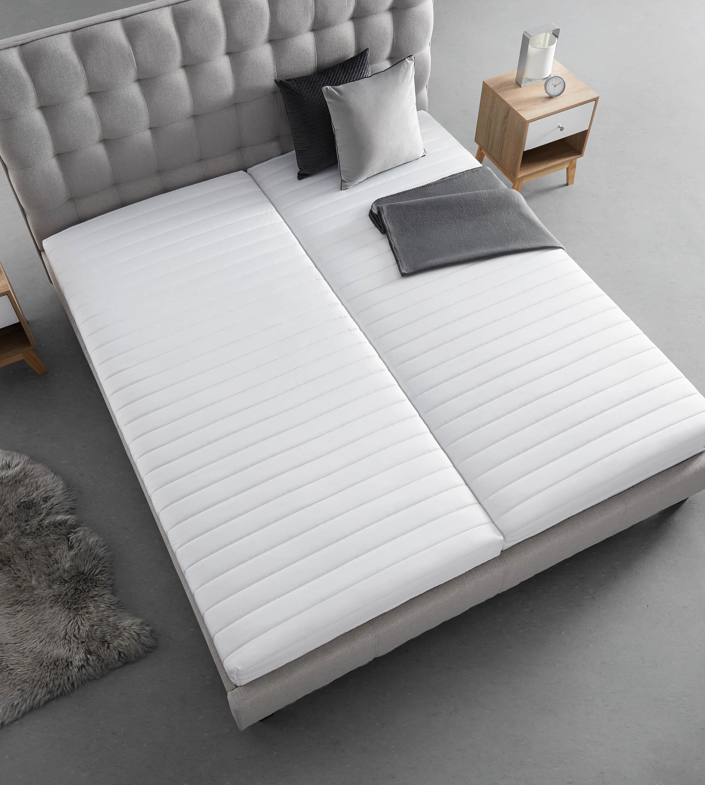 Graues Bett mit zwei Matratzen und Holz-Nachtkästchen