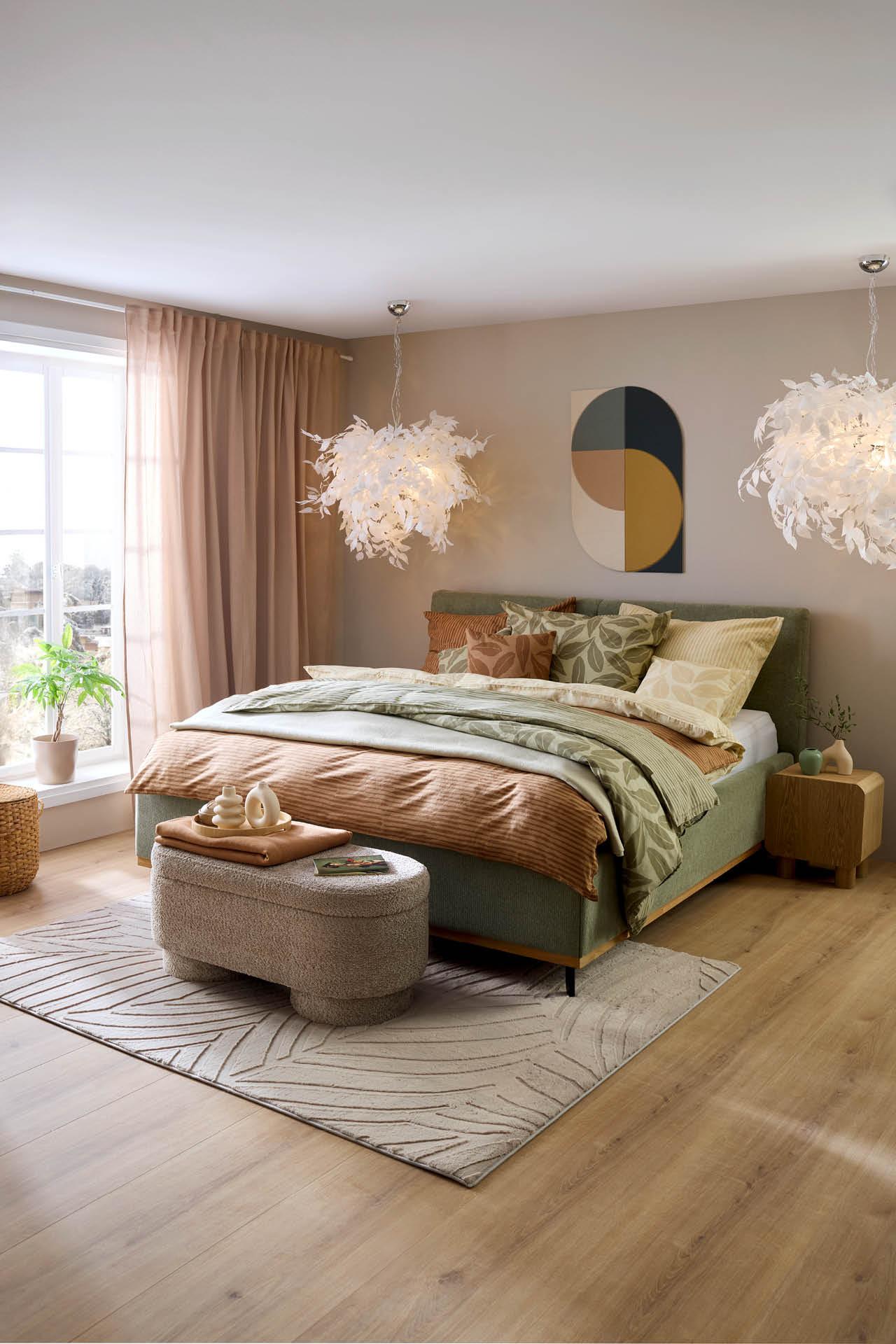 Graues Bett, Hocker davor, gemusterter Teppich