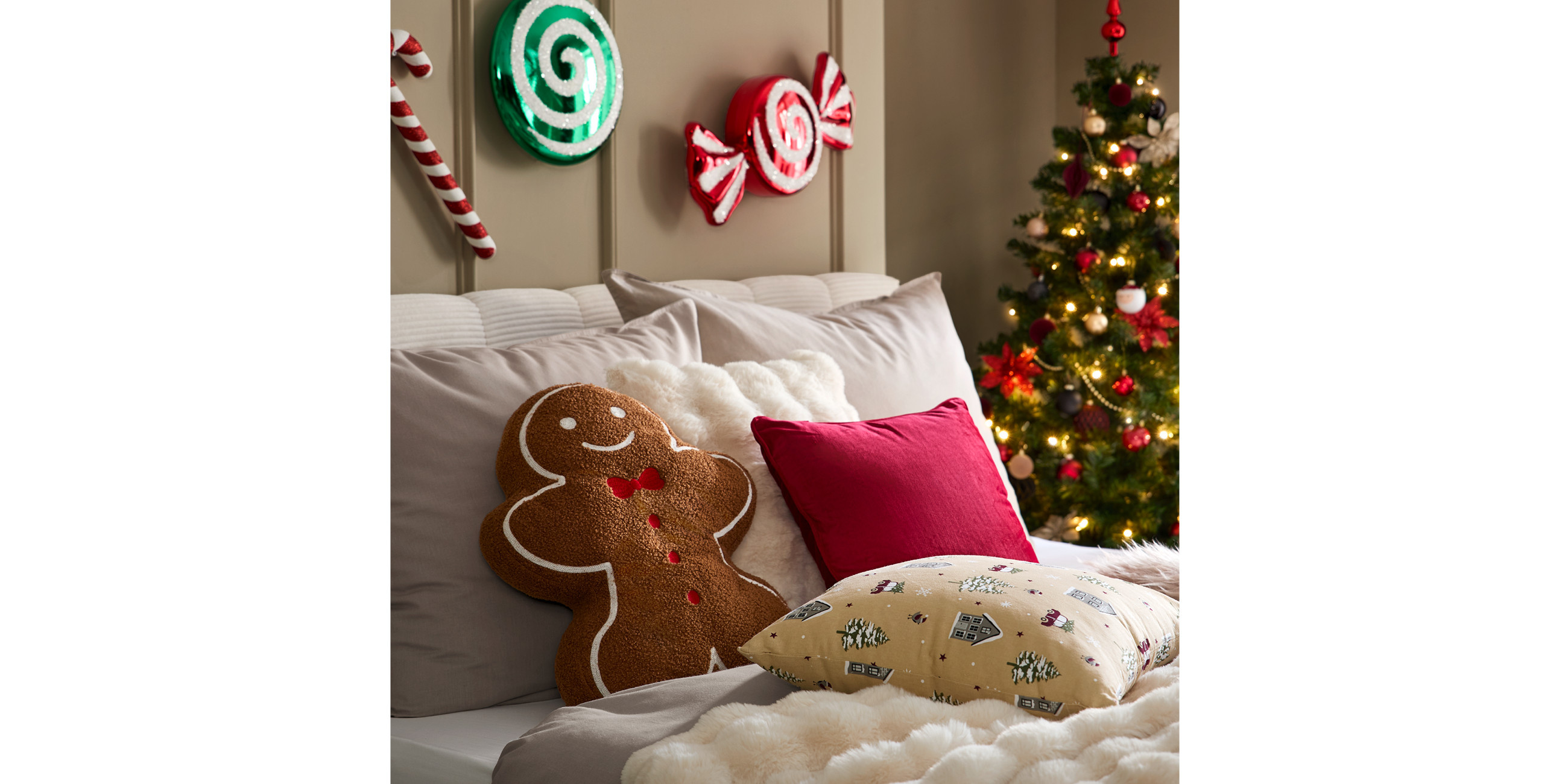 Bett mit rotem Kissen und Kissen in Lebkuchenform, Christbaum im Hintergrund