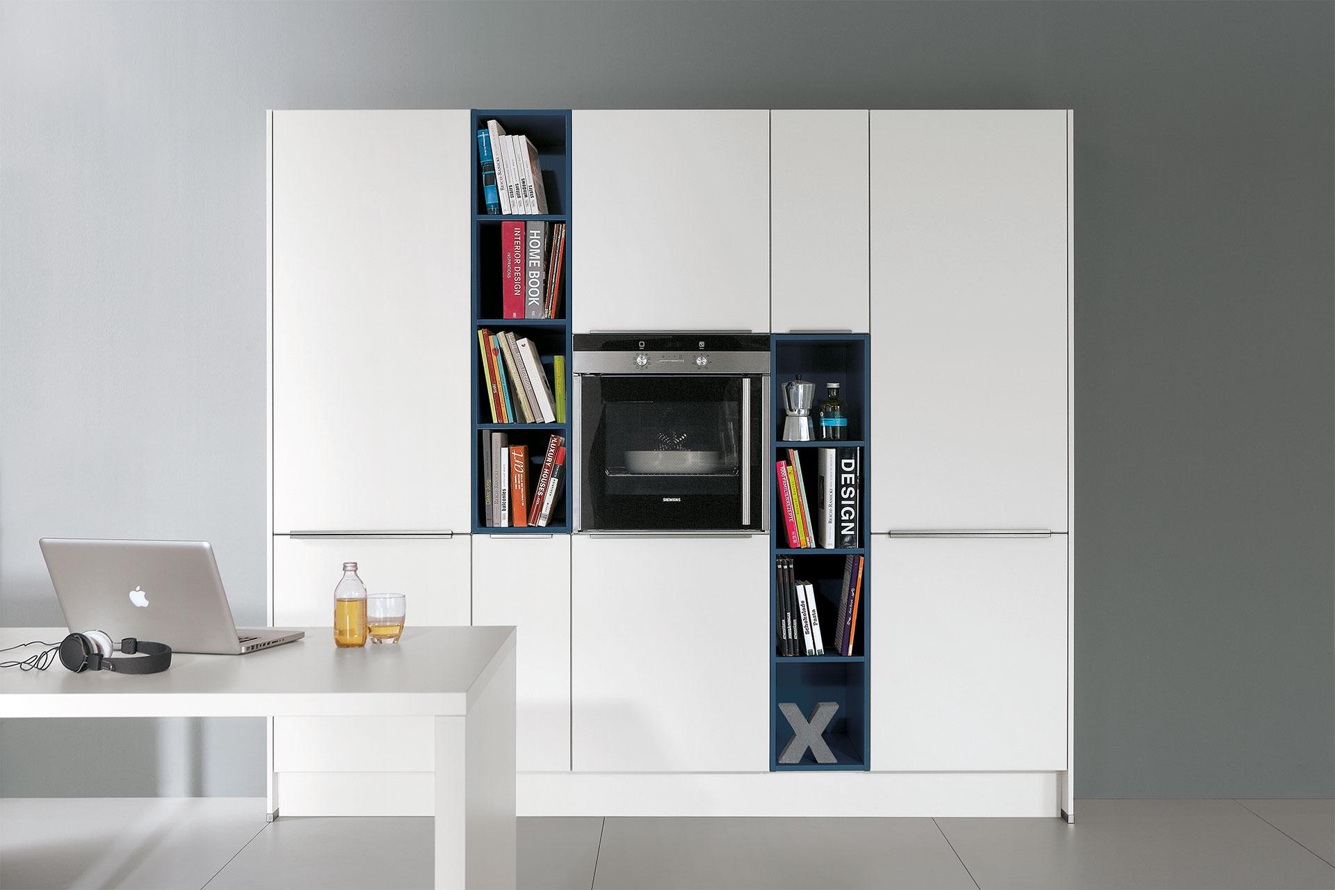Moderne Wohnküche in cleanem Weiß mit integriertem Backofen und Regalen von mömax.jpg