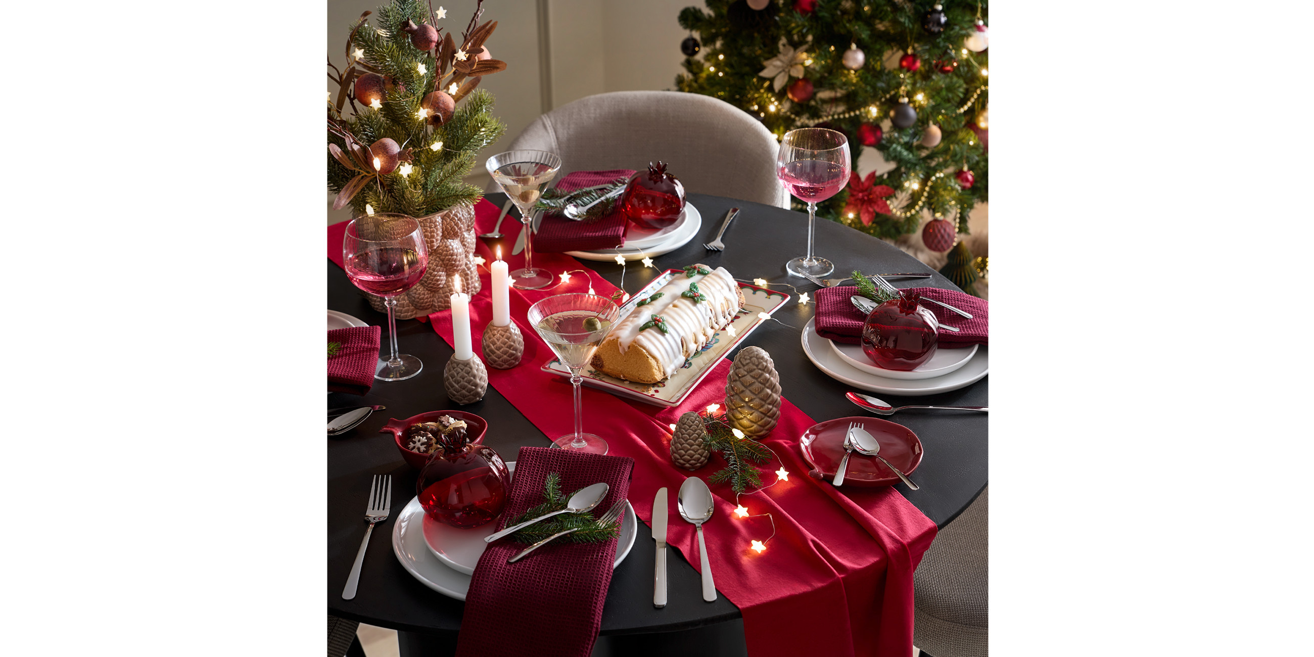 Gedeckter schwarzer Tisch mit rotem Tischläufer und Weihnachtsdeko