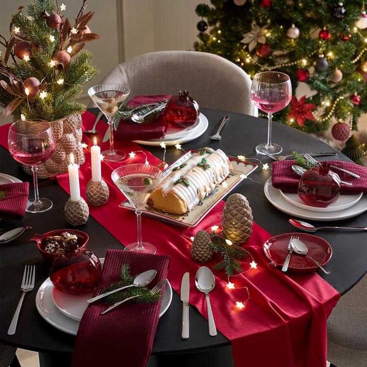 Gedeckter schwarzer Tisch mit rotem Tischläufer und Weihnachtsdeko