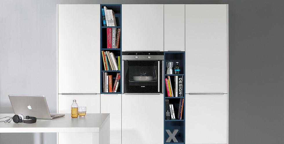 Wohnküche in kühlem Weiß mit integriertem Backofen und Bücherregalen von mömax.