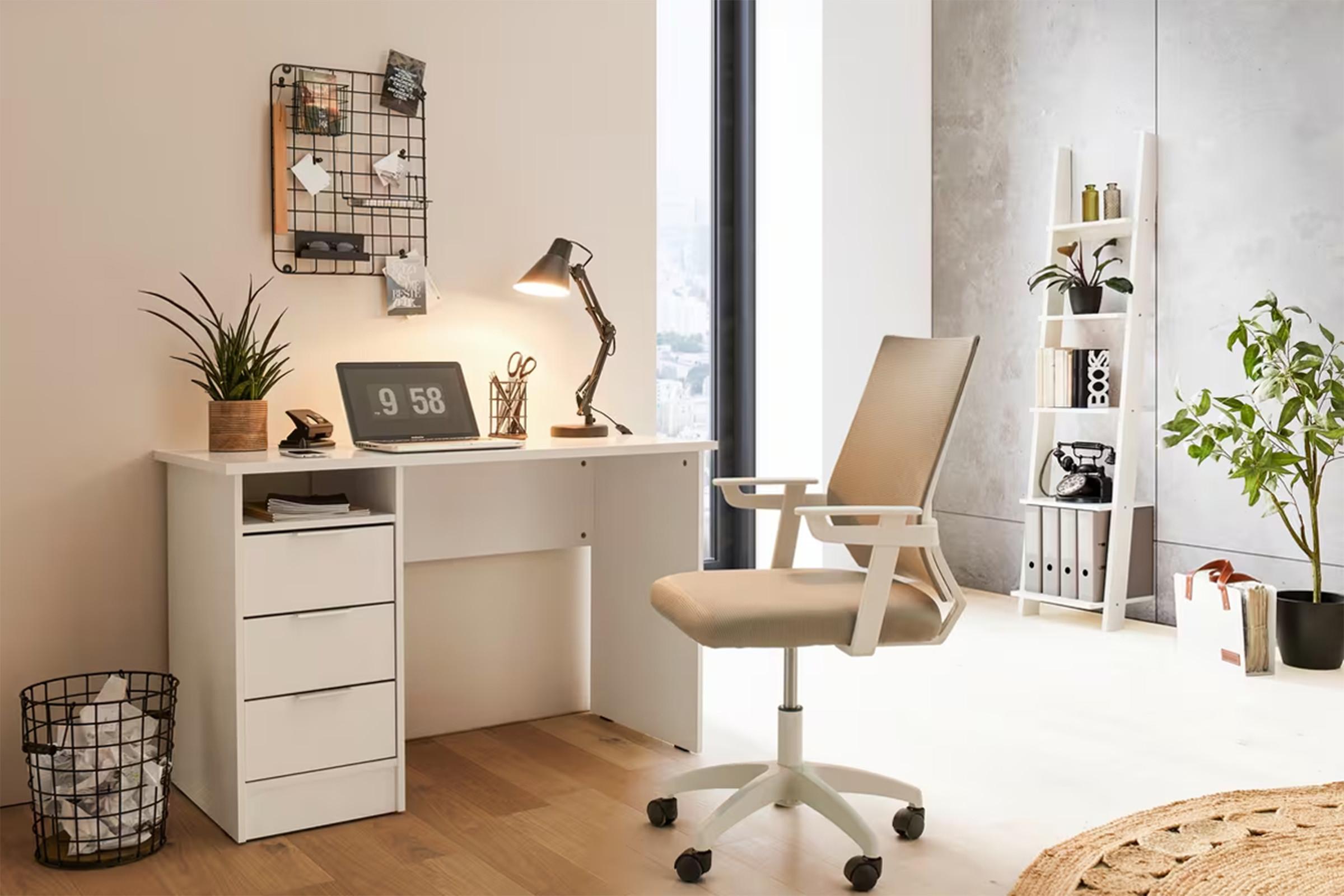 Világos, modern home office: fehér íróasztal fiókos tárolóval, asztali lámpával és forgószékkel, növényekkel a világos térben.