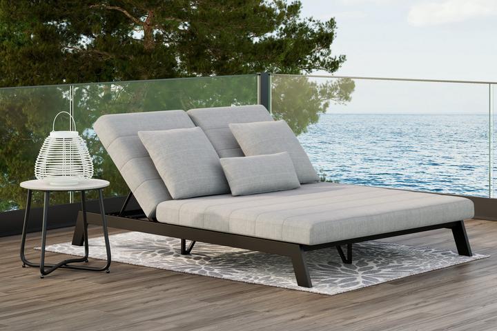 Schwarze Liege mit grauer Auflage auf Terrasse