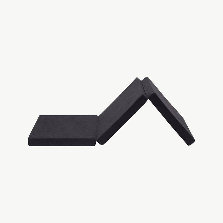 Dunkelgraue Faltmatratze vor grauem Hintergrund