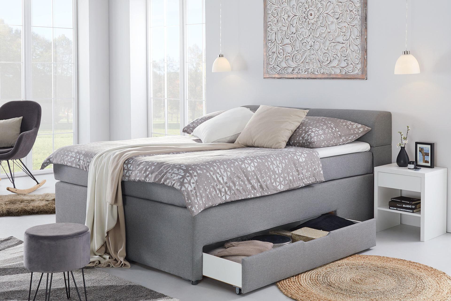 Graues Boxspringbett mit herausziehbarer Schublade im Bettkasten von moemax.
