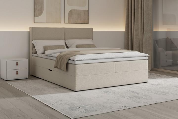 Boxspringbett in Beige mit weißem Nachtkästchen auf weißem Teppich