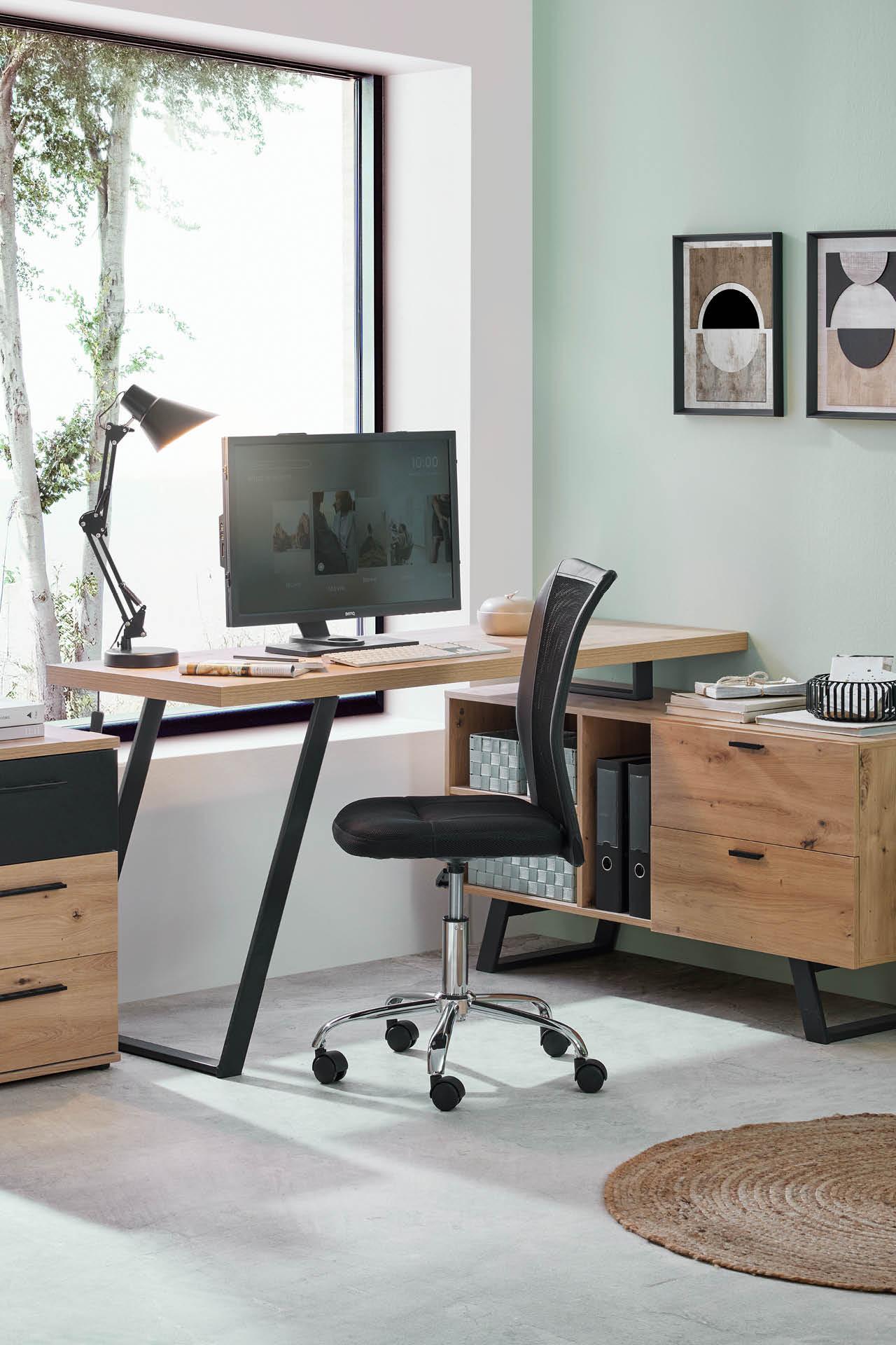 Schreibtisch aus Holz, schwarzer Drehstuhl, Sideboard aus Holz, hellgrüne Wand