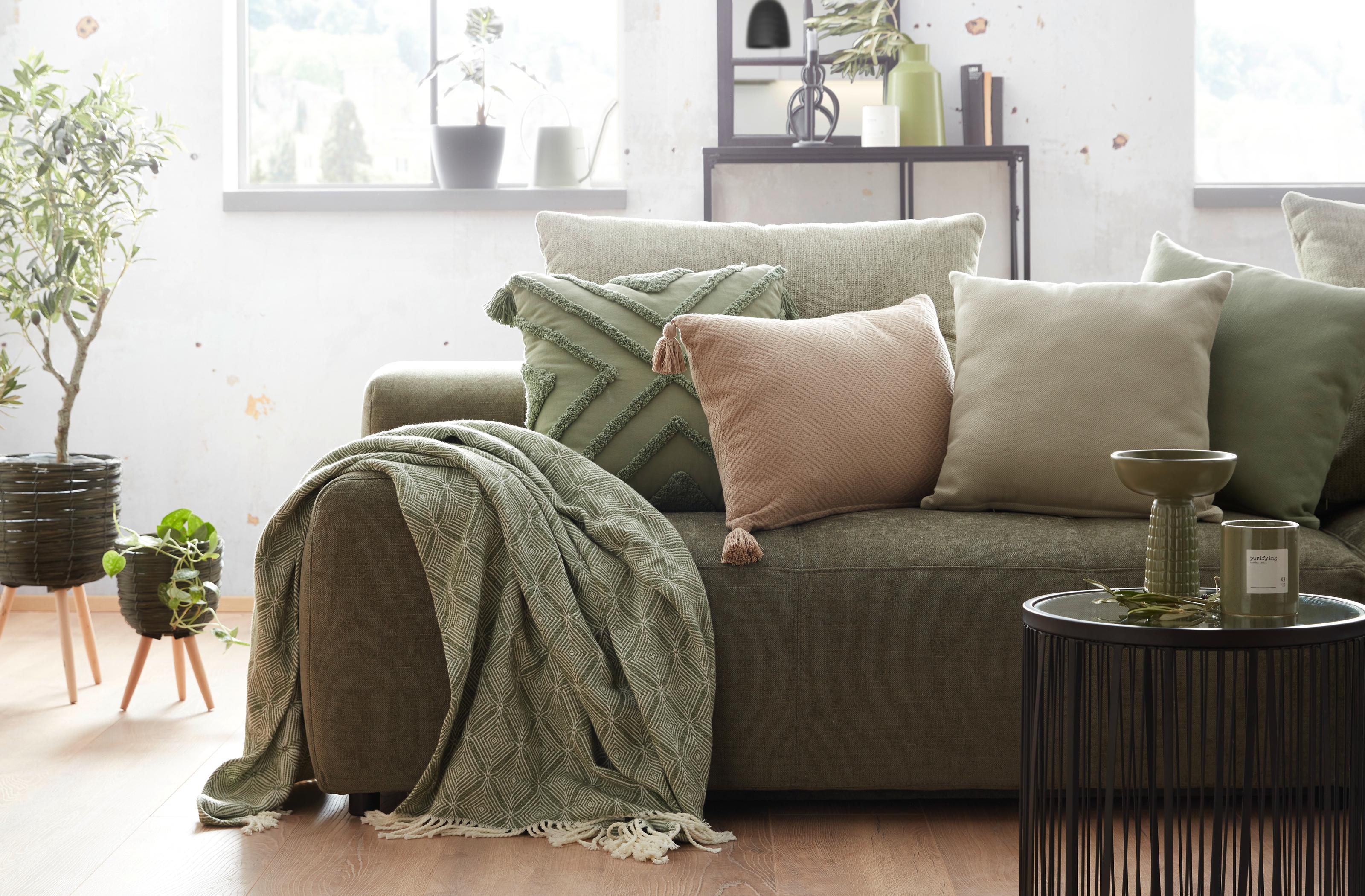 Zielona sofa z dodatkami tekstylnymi