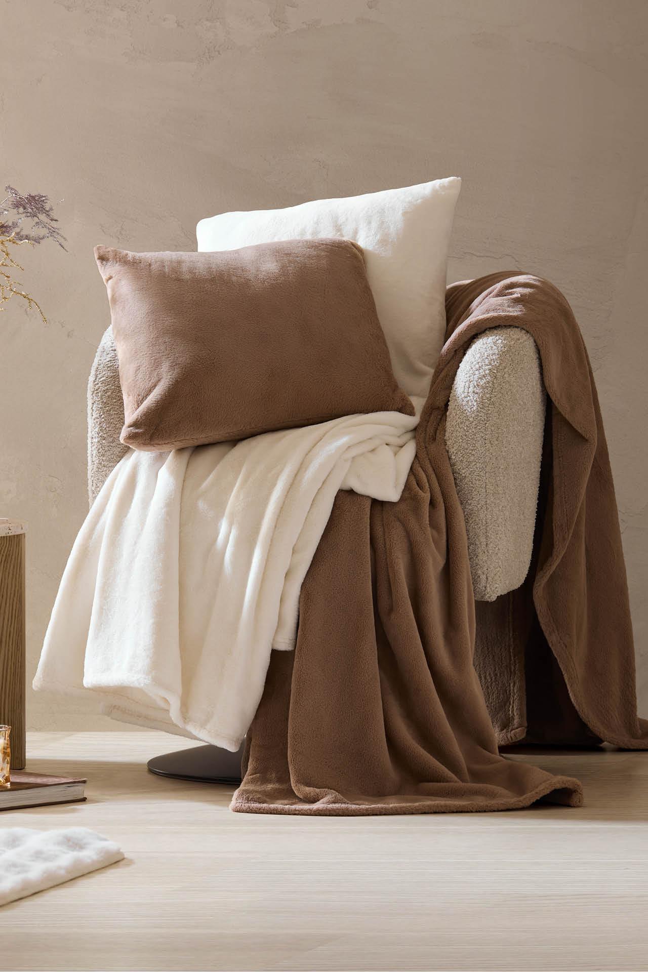 Dunkelbraune Kissen und Decken, helle Kissen und Decken, auf einem Relaxsessel liegend