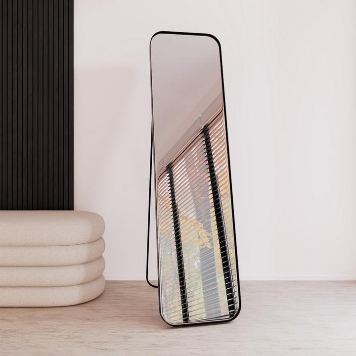 Standspiegel mit schwarzem Rahmen, beige Sitzbank links daneben